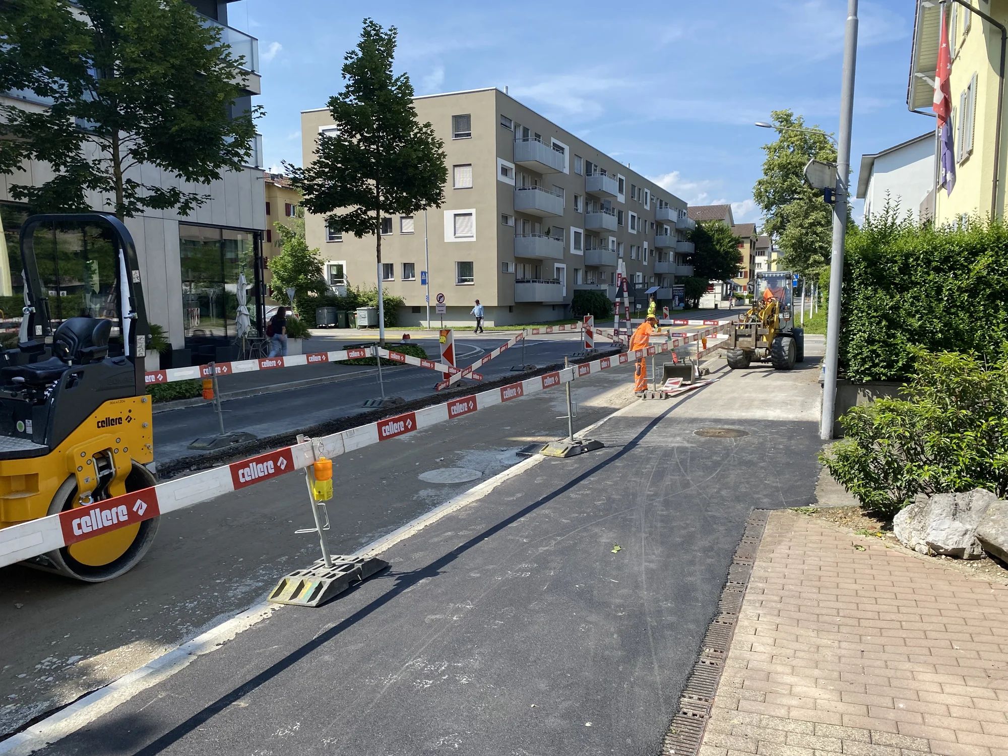 Cordoned-off carriageway on Industriestrasse with a roller and workers laying the surface.