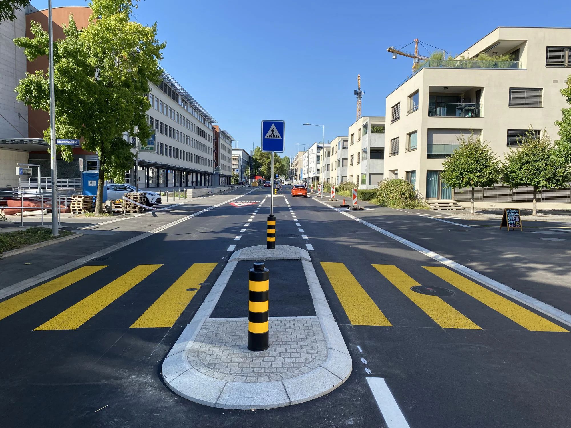 The completed Industriestrasse with a yellow pedestrian crossing and central island.