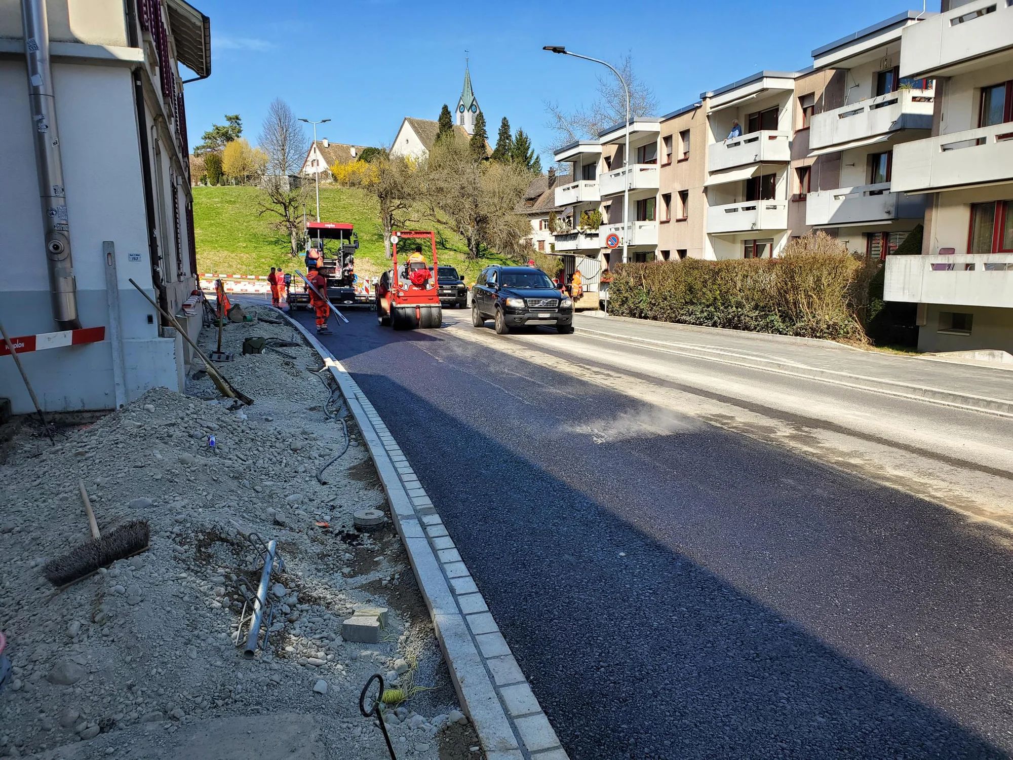 Freshly laid asphalt on Sihlwaldstrasse, next to it the new kerb and the pavement still under construction.