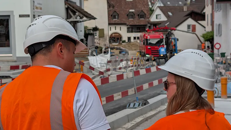 Two employees in high-visibility vests in front of the construction site in Frenkendorf
