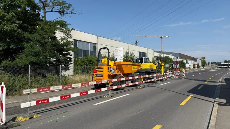 Cordoned-off site on Knonauerstrasse with a dumper and an excavator in front of an industrial building.